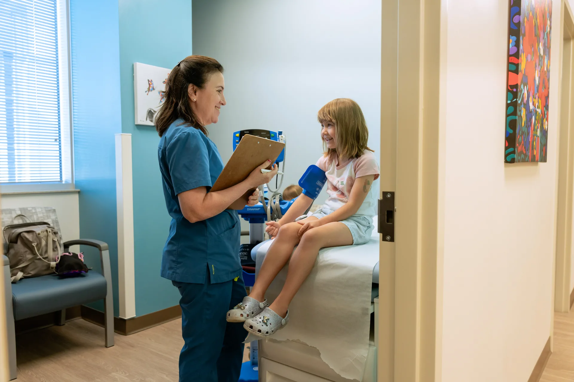 Dr. Aftab Guy talking with a young patient on the exam table during a first visit