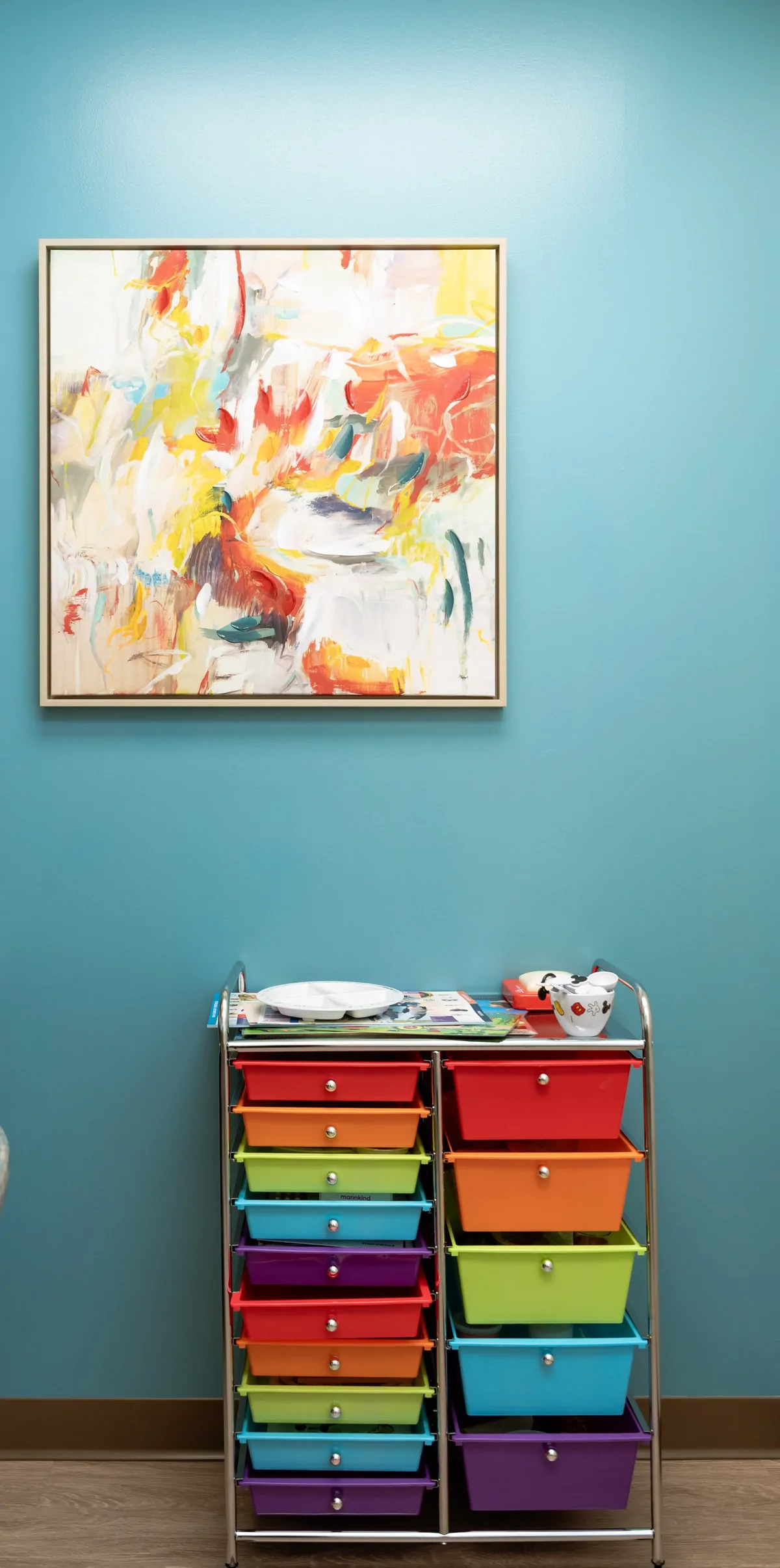 A colorful abstract canvas above the practice art cart