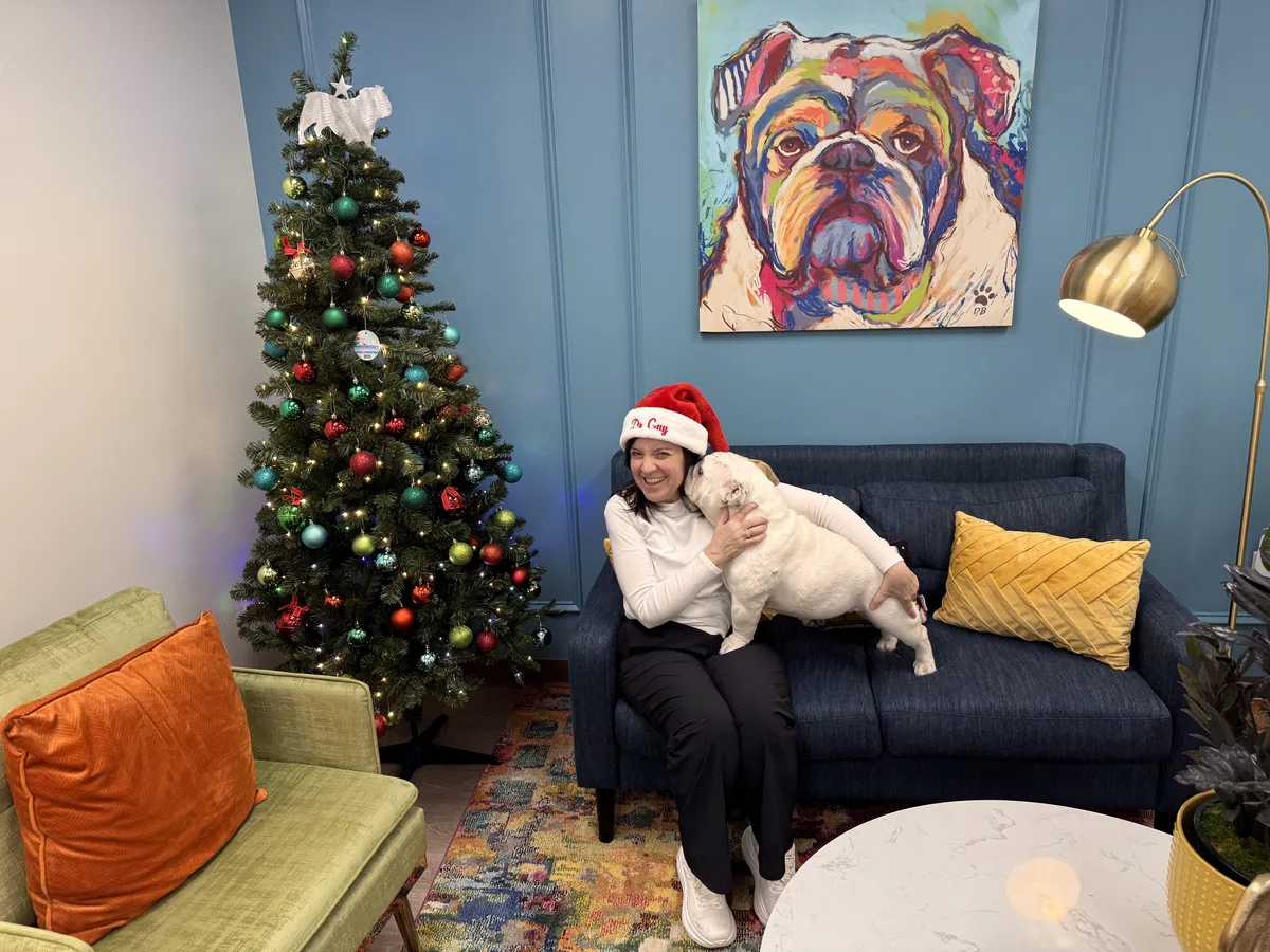 Dr. Aftab Guy with Georgy the therapy dog beside the practice Christmas tree