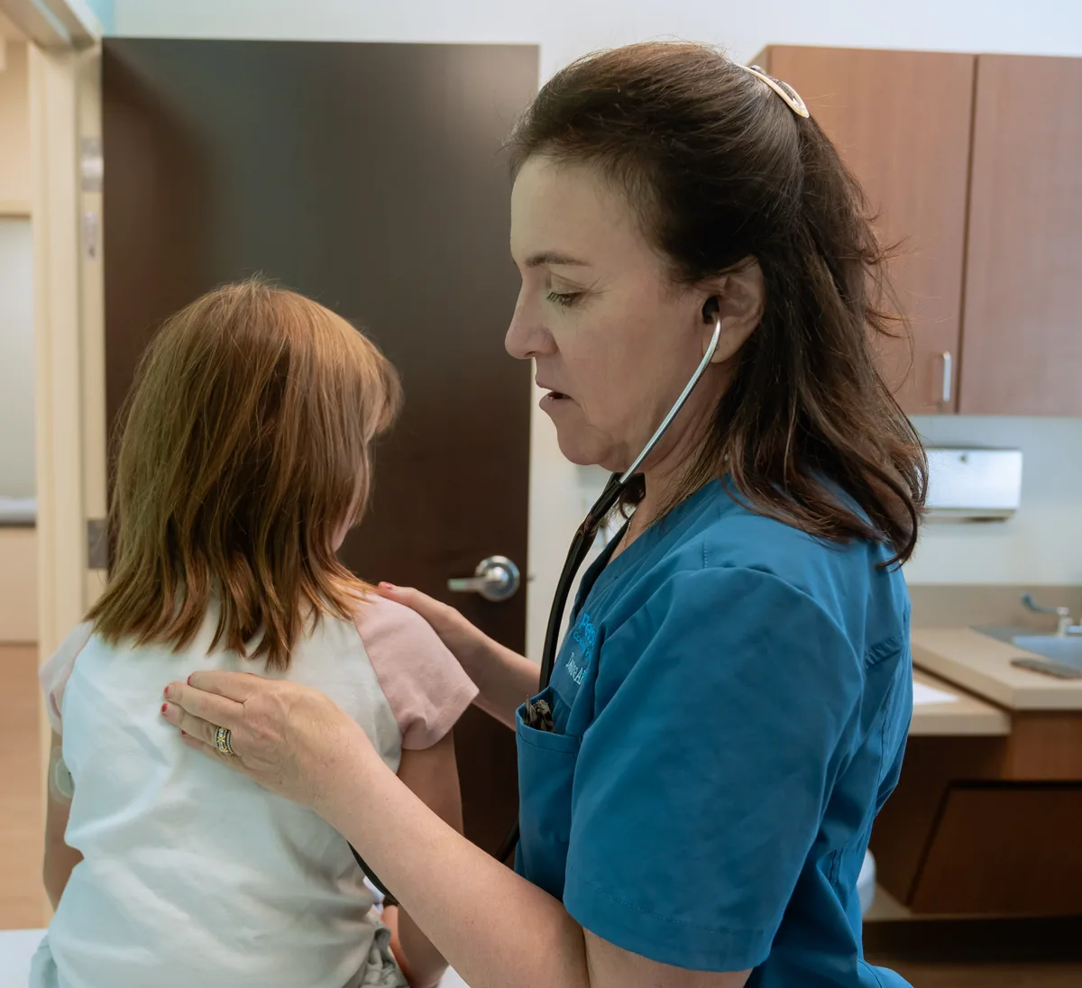 Dr. Aftab Guy examining a young patient with a stethoscope